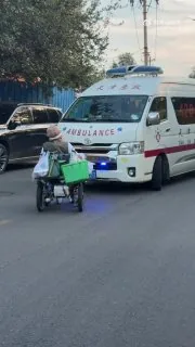 天津街头，一辆正在执行急救任务、鸣笛示警的救护车正常行驶途中，一名乘坐轮椅的大妈刻意拦在车辆前方，迟迟不肯挪开，硬生生挡住了救护车前进路线。